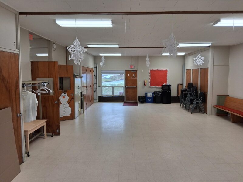 Large empty room with chairs stacked by walls