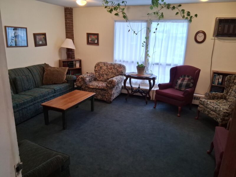 A carpeted room with comfortable chairs and a coffee table