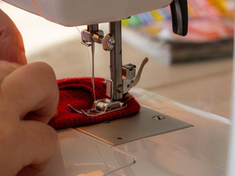 sewing machine foot with hands of person advancing fabric
