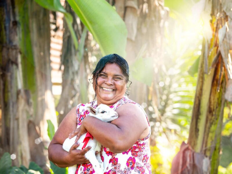 Smiling woman holding a young goat